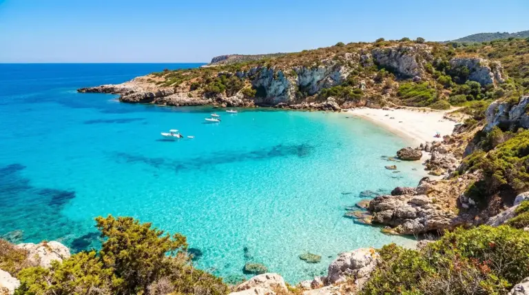 Cala nascosta con mare turchese e barche ormeggiate vicino alla riva in Italia